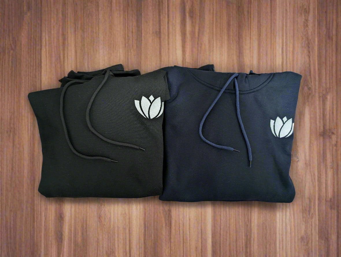 Two black hoodies with white tulip designs on a colorful paisley patterned fabric.