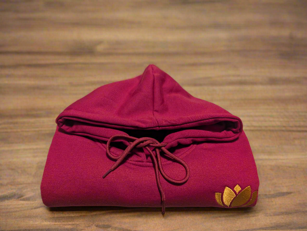 Folded red hoodie with a yellow logo on a beige surface